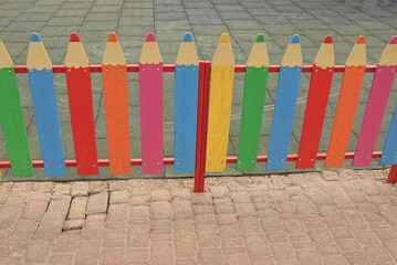 part of a colored decorative wooden fence wall made of boards on a brown pavement in the street