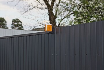 one square orange signal light on a black metal wall fence in the street