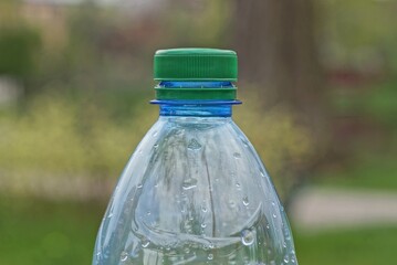 part of one plastic wet bottle closed with a green cork in the street