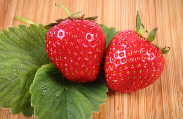 Fresh delicious strawberry with leaves on wooden board. Healthy nutrition