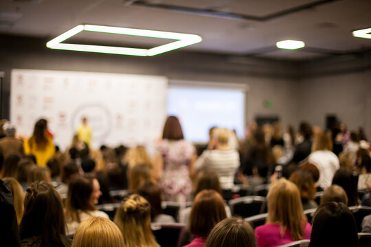 Abstract blurred photo of conference hall or seminar room with speakers on the stage and attendee background, seminar and study concept. Speaker on the podium. People at the conference hall.