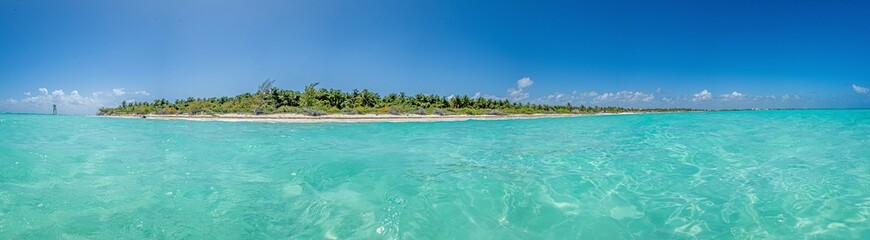 Panorama over a tropical beach taken from the water during the day with sunshine