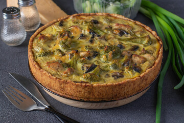 Quiche with chicken, mushrooms and broccoli, homemade traditional french pie on a dark gray background
