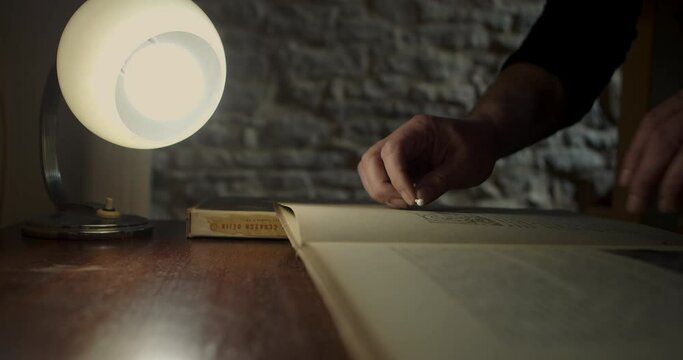 A person cleans very precisely the dirt in an old rare book