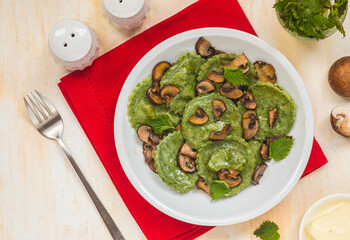 Round nettle ravioli stuffed with mushrooms and curd cheese in a gray ceramic plate on a light concrete background. Recipes with wild herbs.