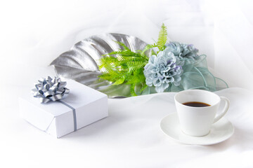 ブルーグレーのダリアの花束と銀色のモンステラとコーヒーとプレゼント（白バック）