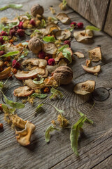 Dried delicious delicacies. Dry pieces of linden, rose hips, pears, raspberries, apples and walnuts snack on a wooden background