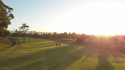 Two diverse male golf players walking at golf course on sunny day