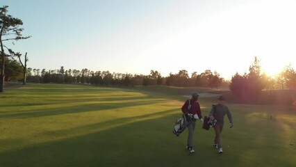Two diverse male golf players walking at golf course on sunny day