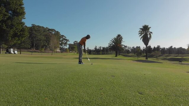 Two Diverse Male Golf Players Playing Golf At Golf Course On Sunny Day