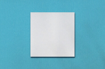 Blank white square or frame for your content on turquoise paper texture. Vivid colour background for your objects. Plain graphics element for further fashion work.