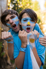 Friends soccer fans painted with the colors of the Argentine team celebrating the goals.