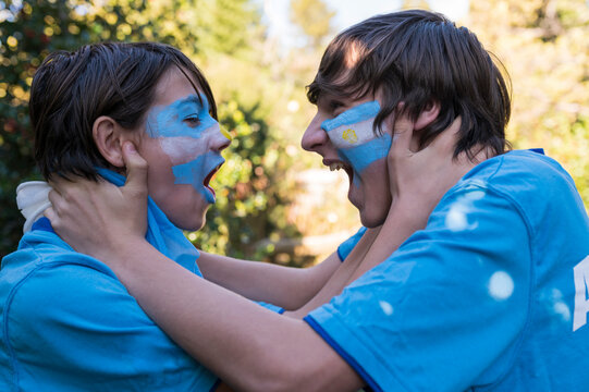 Friends soccer fans painted with the colors of the Argentine team celebrating the goals.
