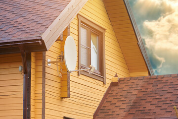 satellite dish antenna outdoor mounted at wall of country house.