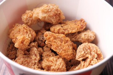 Crispy fried chicken wings in a paper packet on table 