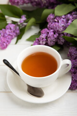 A cup of green tea against the background of a spring bouquet of lilacs on a textured gray background.Romantic composition with books and candles. Spring tea drink. Place to copy.