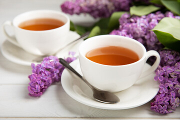 A cup of green tea against the background of a spring bouquet of lilacs on a textured gray background.Romantic composition with books and candles. Spring tea drink. Place to copy.
