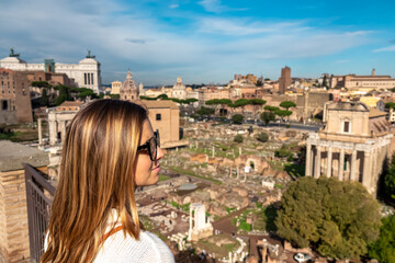 Tourist woman with panoramic view on ancient ruins of Roman Forum. Skyline from Palatine Hill in...