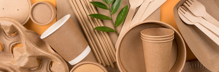 Banner with eco-friendly paper tableware - kraft paper food packaging on orange background. Street food paper packaging, recyclable paperware, zero waste packaging concept. Mockup image