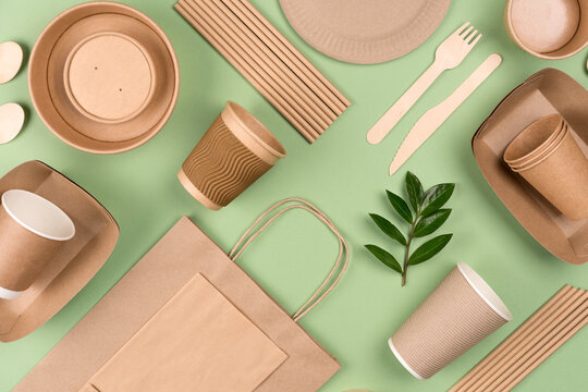 Eco-friendly tableware - kraft paper food packaging on light green background. Street food paper packaging, recyclable paperware, zero waste packaging concept. Flat lay