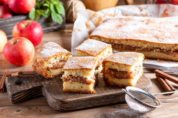 Sponge cake with apples on a wooden board on the wooden table. Homemade pie