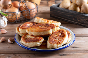 Homemade traditional Russian pies (piroshki) with potatoes filling on table.