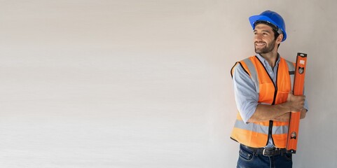The handsome middle eastern American engineer stands alone confidently.holding a level meter, wearing a ppe suit,hard hat.Teamwork target successful concept.Foreman Handsome cement wall.Banner cover.