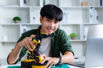 Asian teenager constructing robot arm homework project in house. technology of robotics programing...