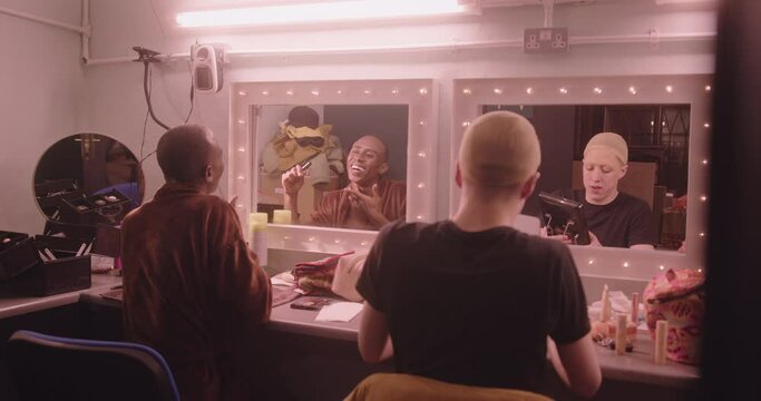 Group of Non-Binary People Backstage, looking in Mirror Applying Make up