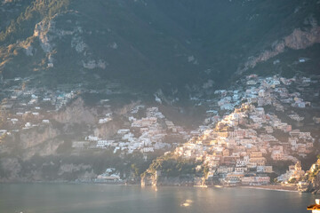 Panoramic view during sunset from Praiano to the coastal town Positano, Amalfi Coast, Campania, Italy, Europe. Looking at colorful houses at coastline of Mediterranean Sea at golden hour before sunset