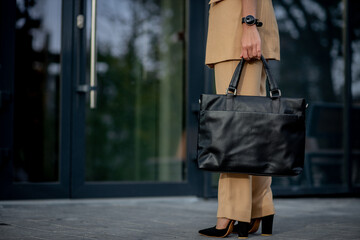 Business lady holding a laptop bag going to the office. Display of businesswoman on modern buildings in the city