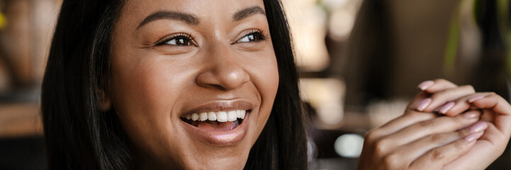 Fototapeta premium Black young woman laughing and looking aside indoors