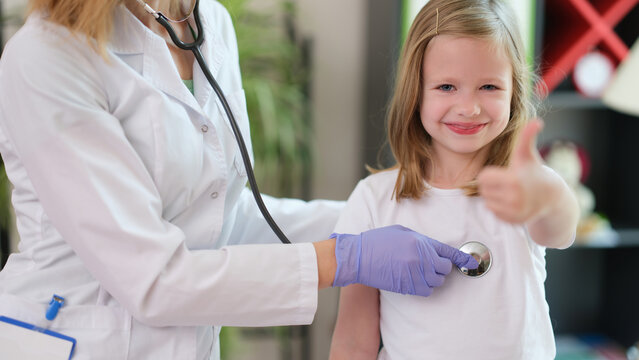 Little girl child making thumbs up gesture at doctor appointment
