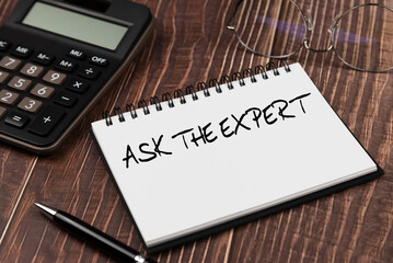 Ask the expert text on note pad with calculator and pen on wood background business and financial concept