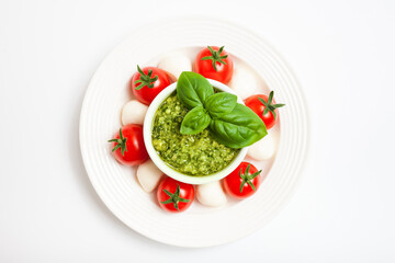 Delicious caprese salad with cherry  tomatoes, mozzarella cheese, pesto sauce,  fresh basil leaves. Italian food. Top view. 