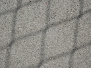 a flat surface of gray concrete, illuminated with a visible shadow in a checkered pattern