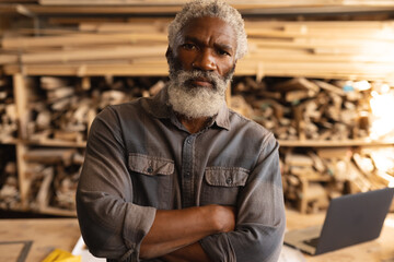 Portrait of confident african american mature carpenter with arms crossed in workshop