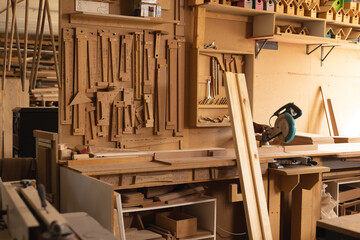 Interior of workshop with planks and various woodworking tools hanging on rack in workshop