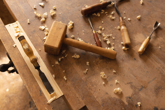 High angle view of mallet and various hand tools with wood shavings in workshop