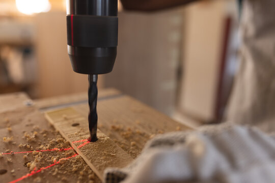 African american mature carpenter making hole with drill on plank at workshop