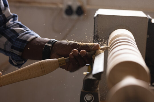 Cropped image of african american mature carpenter shaping and carving wood at workshop