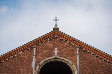 Saint Ambrogio church details, red brick abbey with a big cross at overcast day, Milan, Lombardy,...