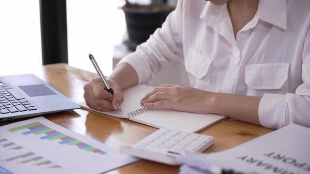 business woman or accountant who are using a calculator to calculate business data Accounting documents and laptop computer at the office business idea	