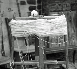 antique wooden spinning wheel with the skein of wool below and the ball of yarn above with an...