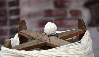 ball of wool just created with an ancient wooden spinning wheel by the weaver