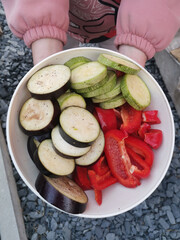 sliced vegetables in a white plate in the hands of a girl, close-up.
