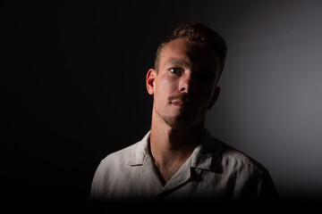 Portrait of a boy in the dark, half of the face in shadow, pensive and gloomy mood.