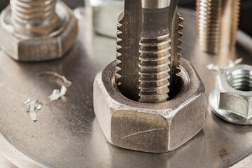 Thread tap drill steel billet with drill bit on background. Working cutter.
