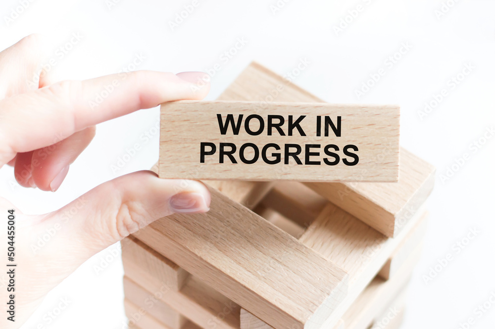 Poster work in progress text on a wooden brace in the hands of a person on a light background