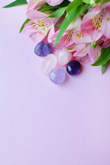 Beautiful pink alstroemeria flowers and semi-precious stones rose quartz and amethyst lie on a pink...